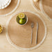 Natural woven round placemat with a lime bowl and cutlery