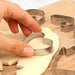 Hand pressing a heart cookie cutter into rolled dough