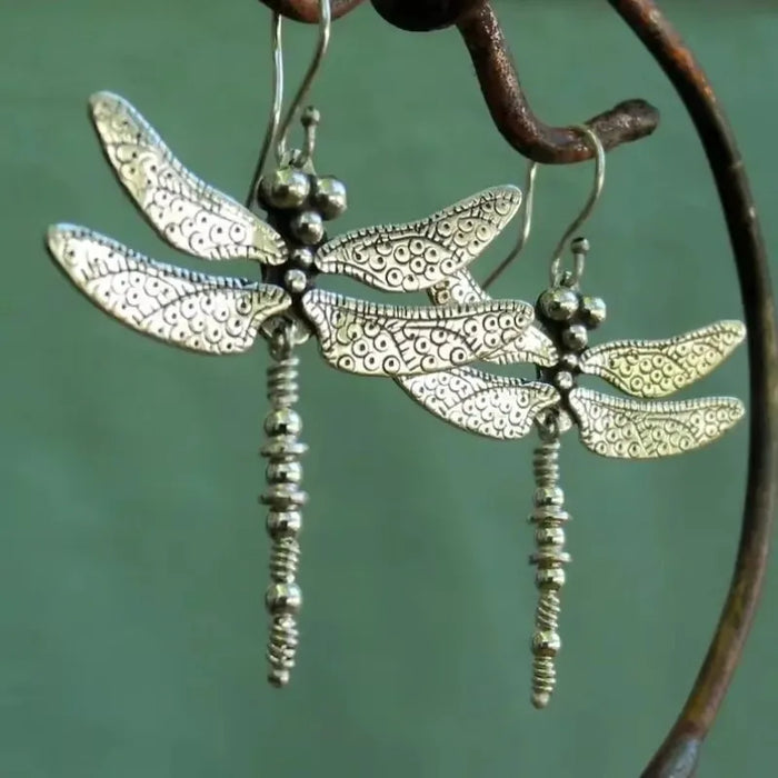 Silver dragonfly earrings close-up on a branch