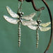 Silver dragonfly earrings close-up on a branch