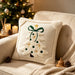Beige embroidered Christmas tree cushion on a cream chair