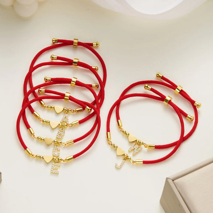 Several red cord initial bracelets on a table