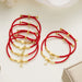 Several red cord initial bracelets on a table