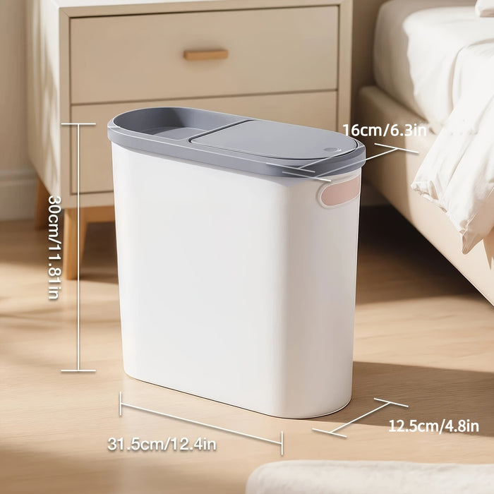 White trash bin with gray lid on a wooden floor in a bedroom setting, with measurements indicated.